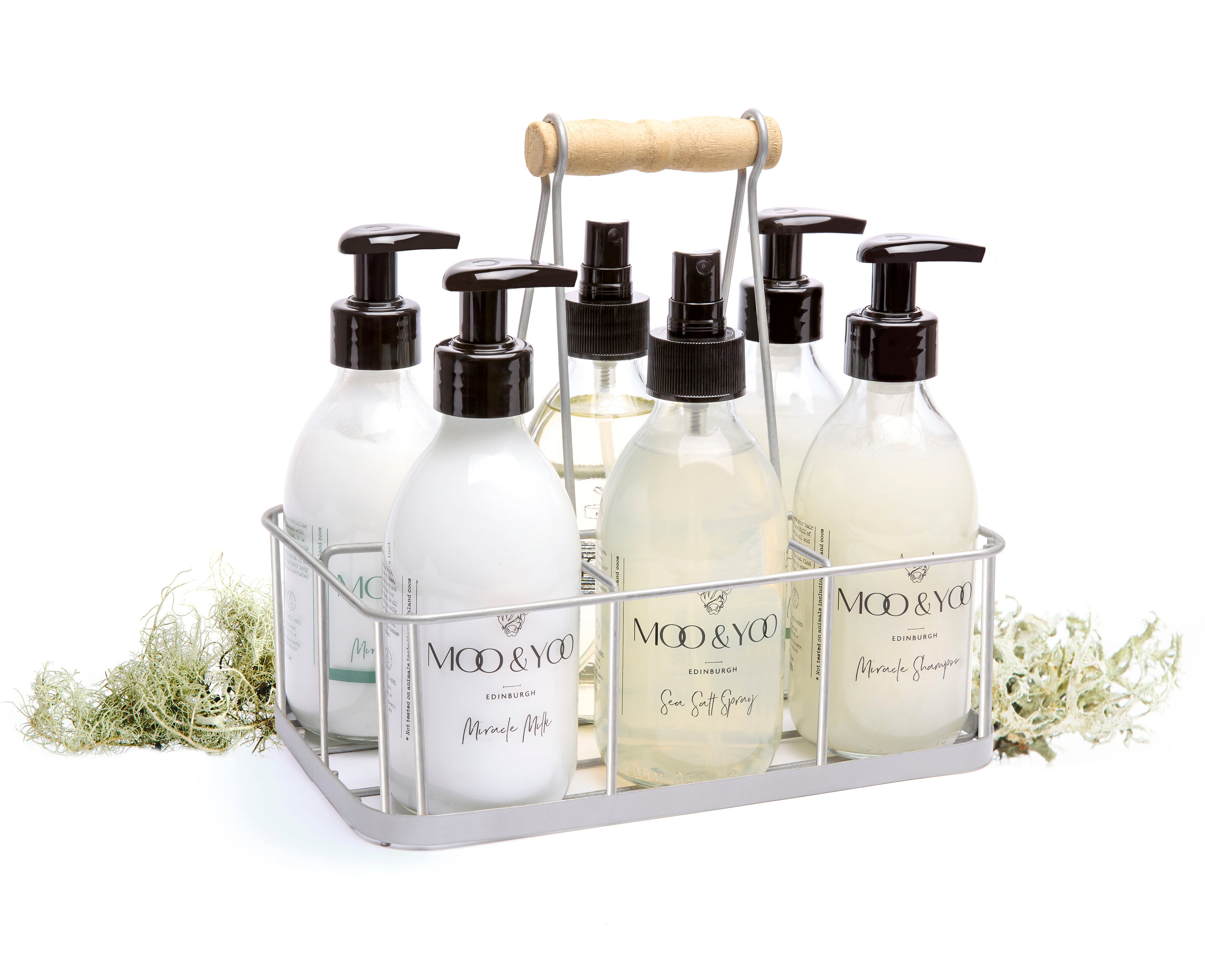 A metal crate containing 6 Moo & Yoo products is sitting in the centre of the image with some moss placed behind it. The image has a plain white background.
