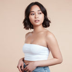 Female model with a wavy bob and brunette hair. She has super shiny hair and has used Moo & Yoo Miracle Shampoo, Conditioner and Volumising Spray Mist. She is looking at the camera and is wearing a white bandeau top.