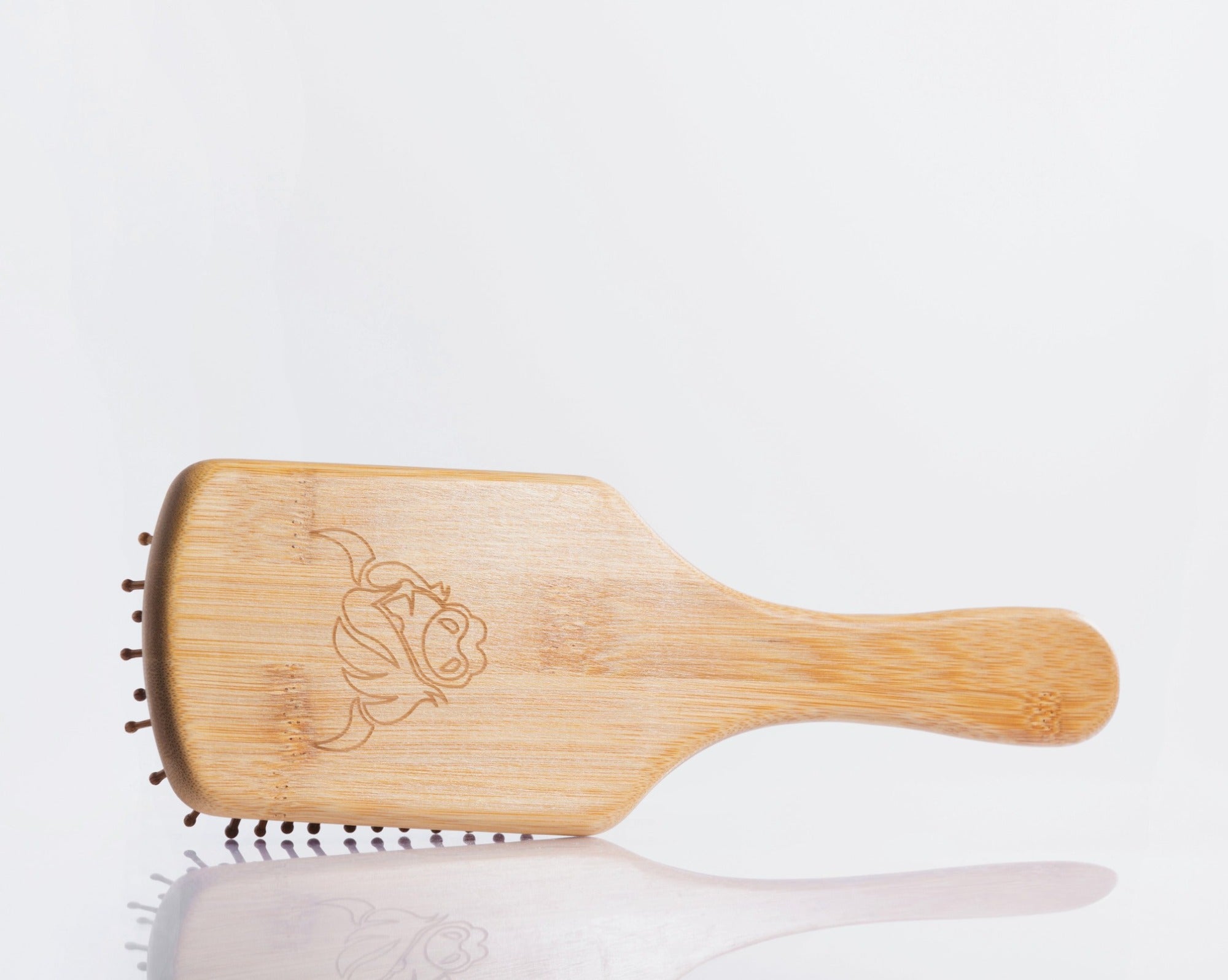 Moo and Yoo bamboo paddle brush showing the cow head logo on the back.