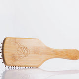 Moo and Yoo bamboo paddle brush showing the cow head logo on the back.