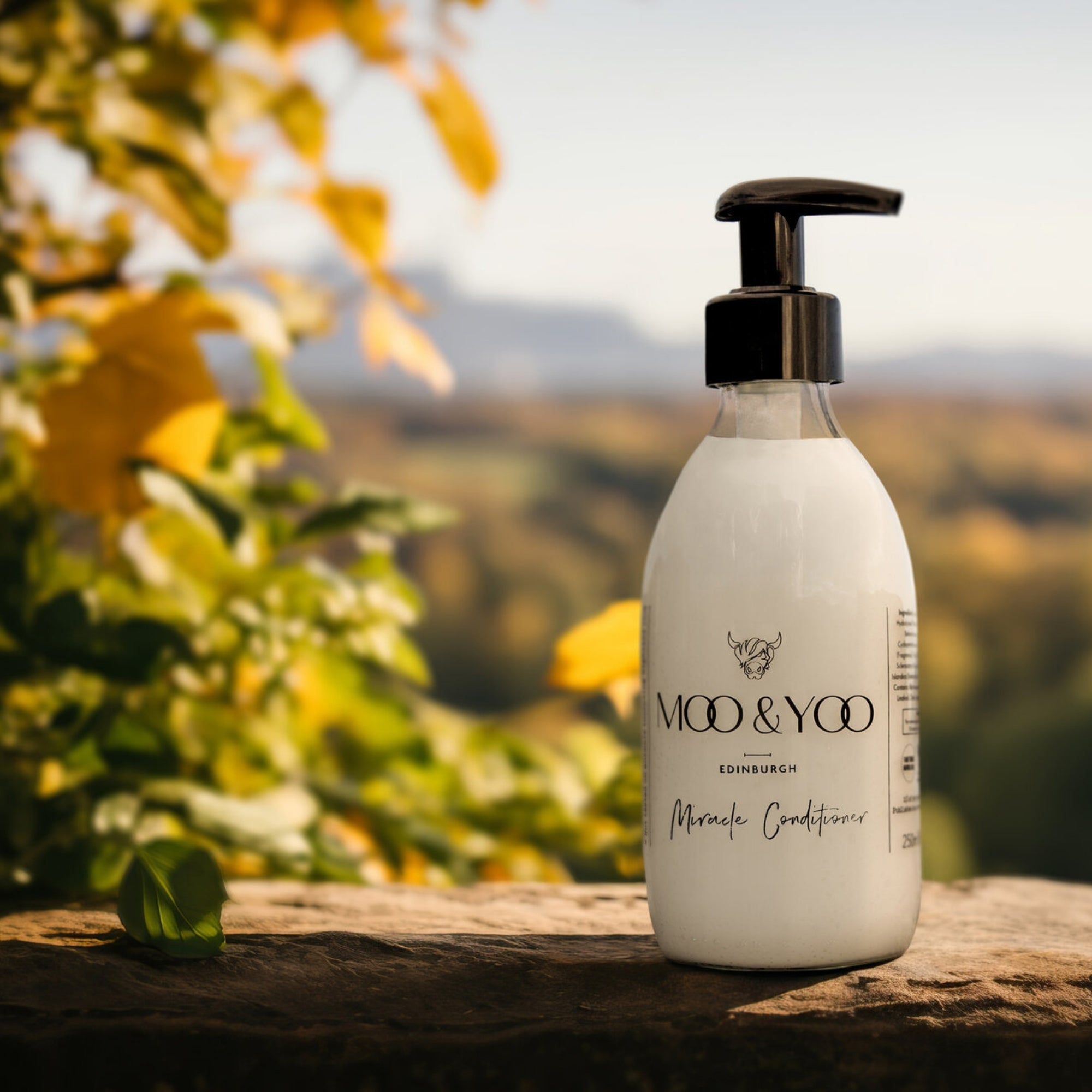 Bottle of MOO & YOO Miracle Conditioner on a stone wall with a natural background