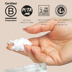 Hand holding a small amount of hair mask with sustainability certification logos on a beige background