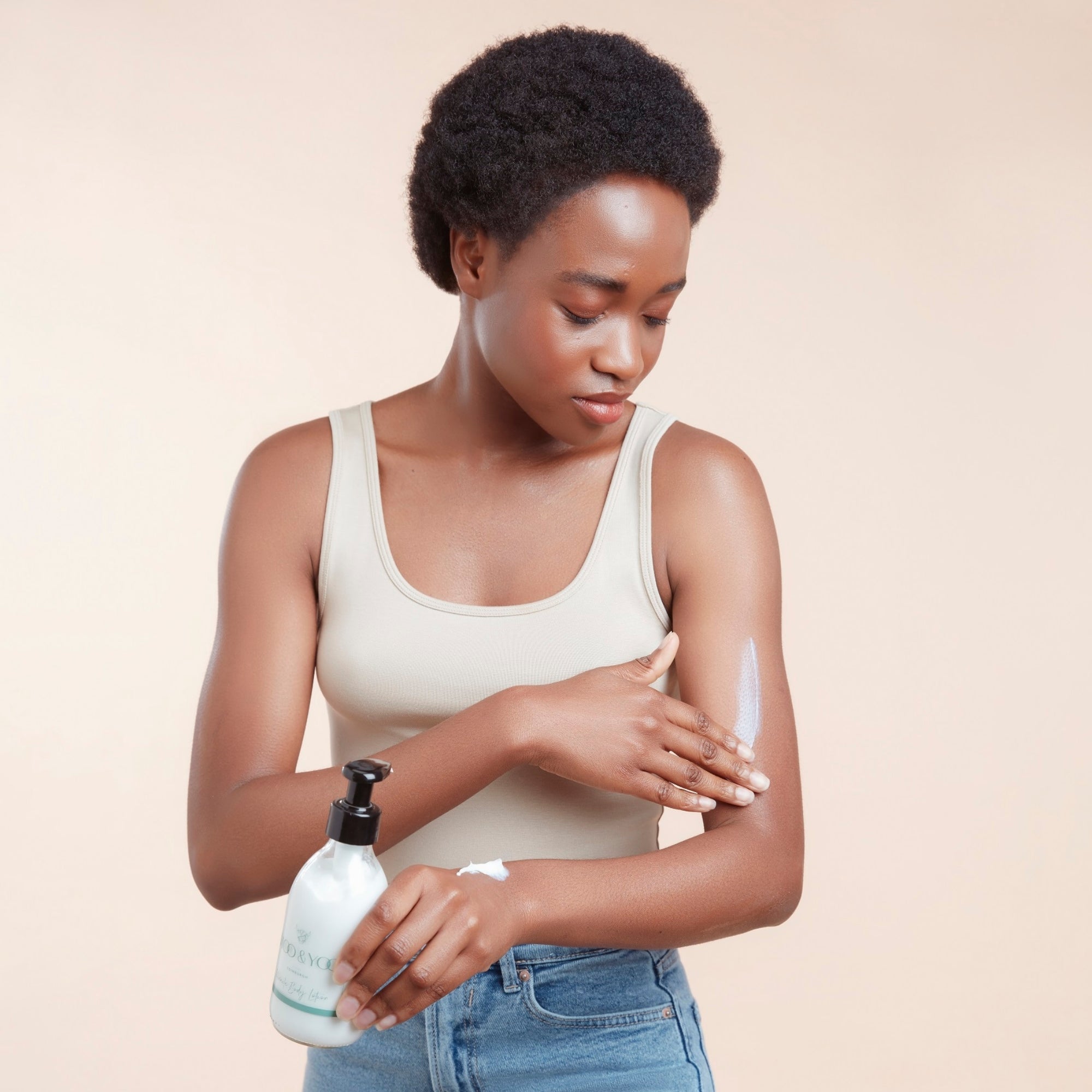 Woman applying moo & yoo miracle body lotion to her arm with a beige background
