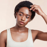 Female model with black natural textured hair from using Moo and Yoo Miracle Mask, Miracle Milk and Miracle Curl Crea,. She has her left hand touching her hair.