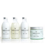 Three glass bottles and a glass jar of Moo and Yoo products sitting side by side. It is a Miracle Shampoo, Conditioner, Miracle Milk and a Miracle mask. They all have aluminium lids.  They are on a white background.