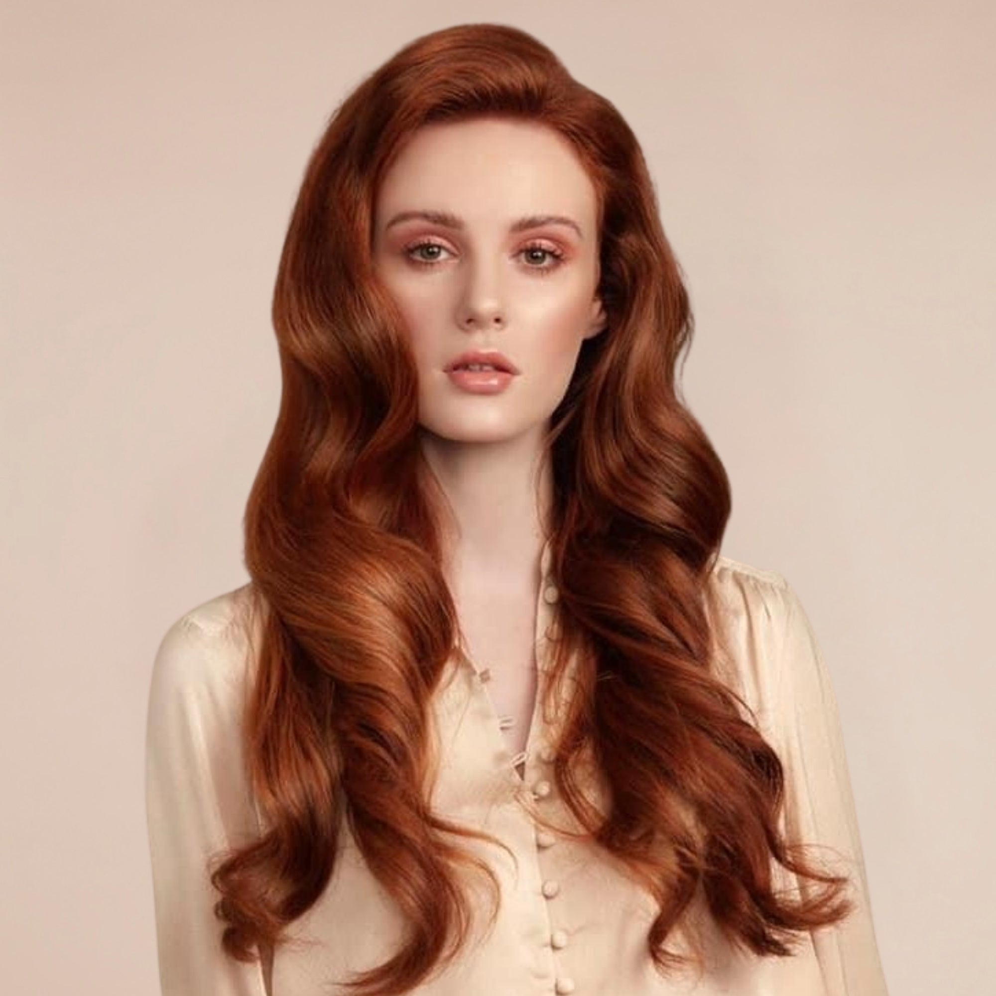 Woman with long, wavy red hair wearing a light-colored blouse against a beige background