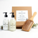 Image of a Kraft natural brown square gift box with label on the front displaying the gift box name which is Elementals. The contents of the box are in front of it, Miracle Shampoo, Miracle Conditioner and Bamboo Paddle Brush.
