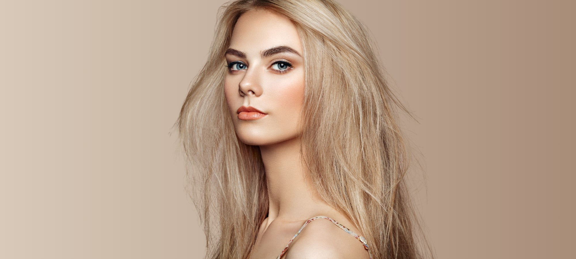 Girl with blonde Type 2B hair looking towards the camera against a beige background.