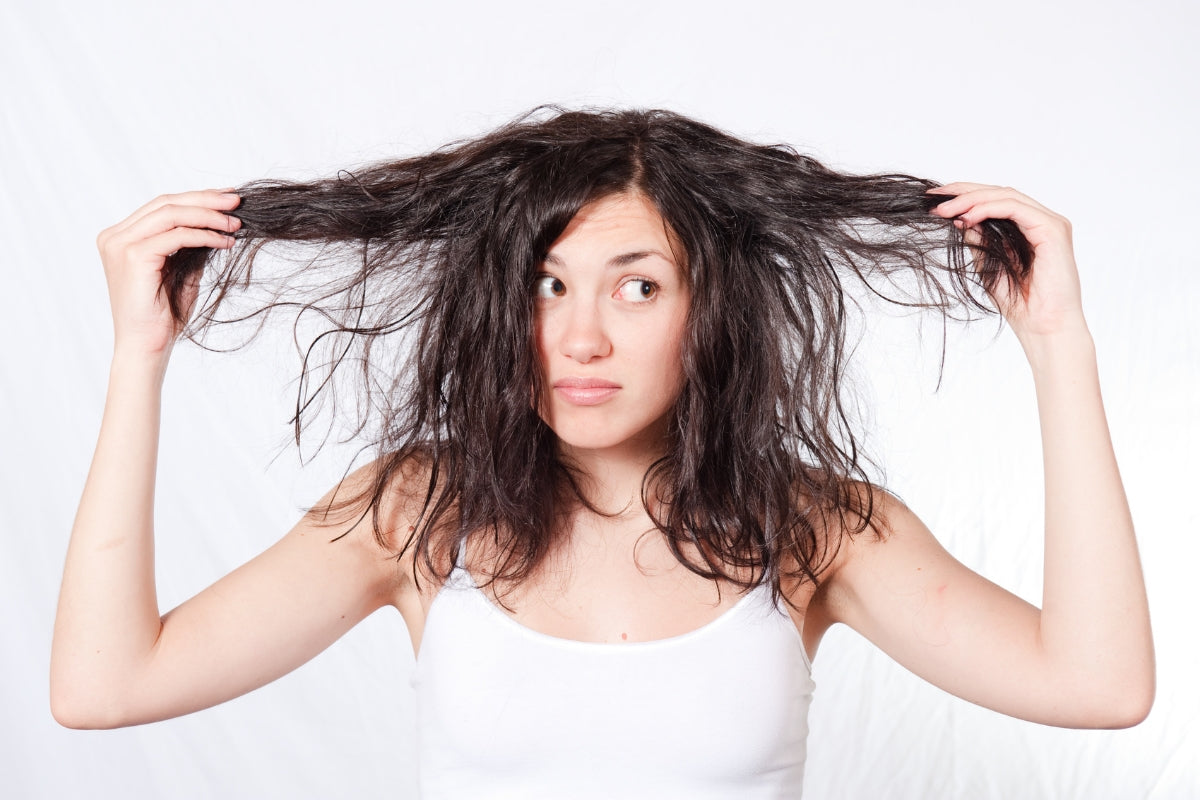 A woman is holding up her hair and making a confused facial expression.