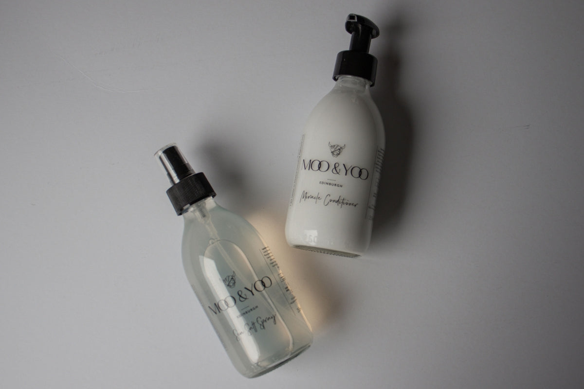 2 Moo & Yoo products are laying on a white surface. The lighting is fairly dark and the products are casting shadows on the background.