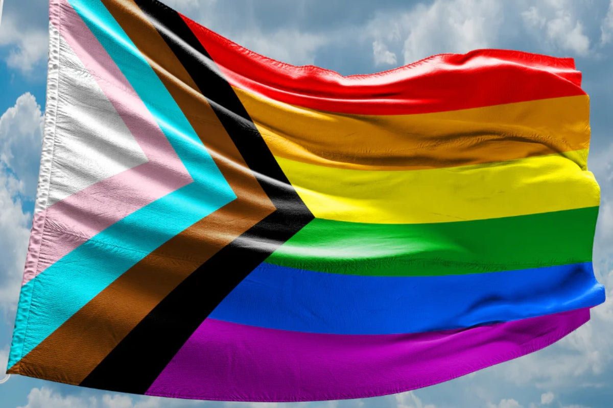 pride flag waving in the wind against a blue sky
