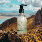 Glass Bottle of Moo and Yoo Body Wash on a rock on top of a Scottish hill overlooking a loch