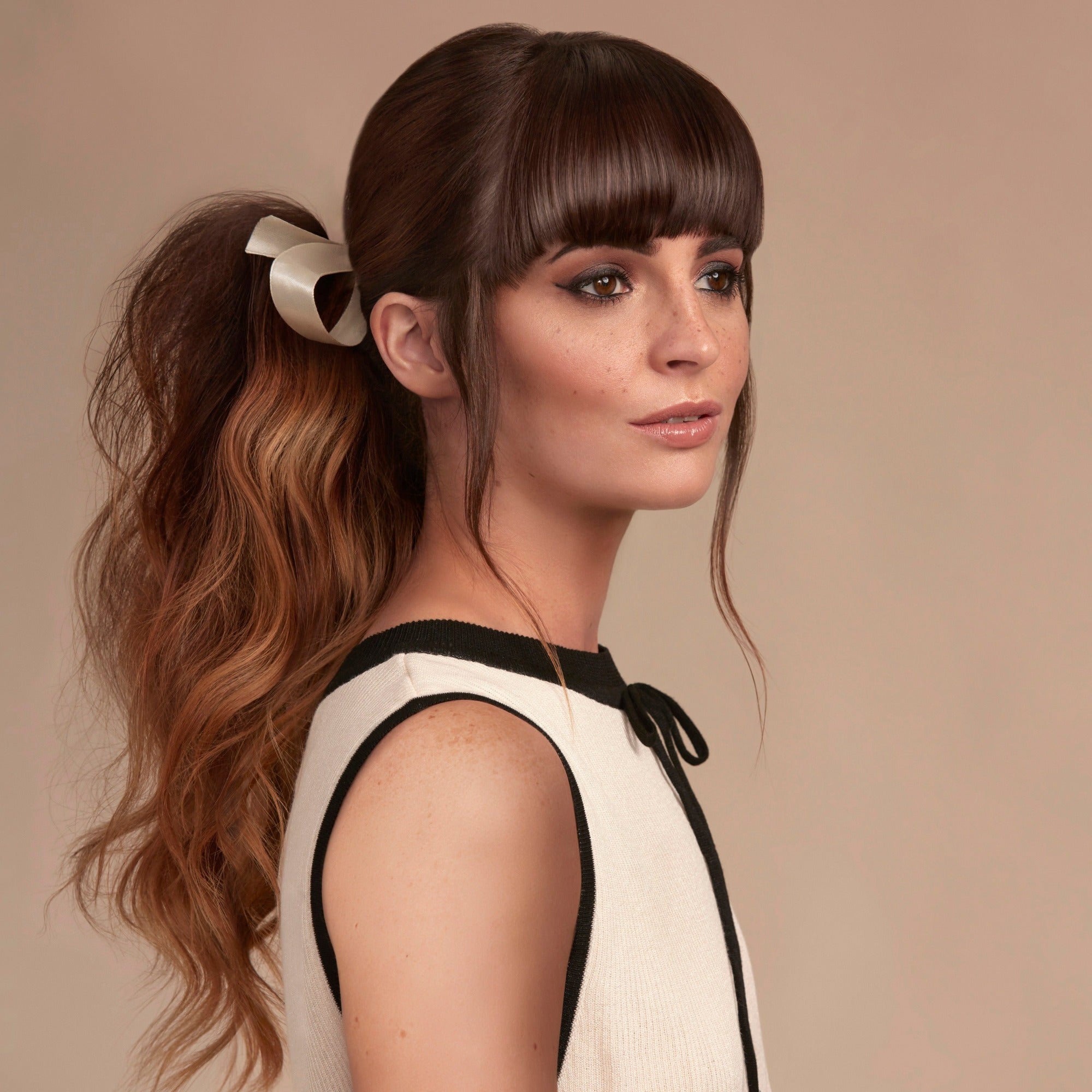 Female model with long wavy brunette hair tied into a low pony tail with a cream ribbon.  Her hair is very shiny from using Moo and Yoo Miracle Conditioner, Mircle Milk and Mask. She is wearing a simple white dress with black trim.