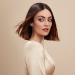 Female model with a super straight brunette bob from using Moo and Yoo Miracle Conditioner and Miracle Milk She has super shiny hair. She is looking at the camera and is wearing a neutral coloured blouse.