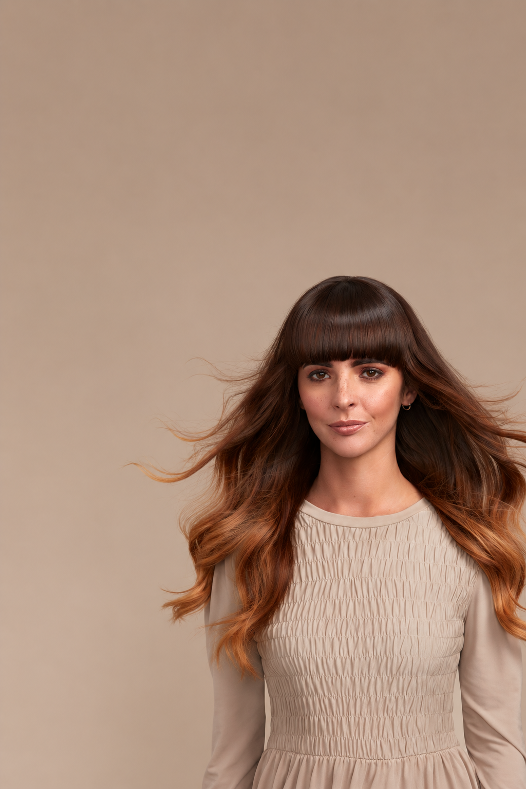 girl with long flowing brunette hair flowing in the wind with a sleek shiny straight fringe facing the camera directly. Natural skin and freckles 
