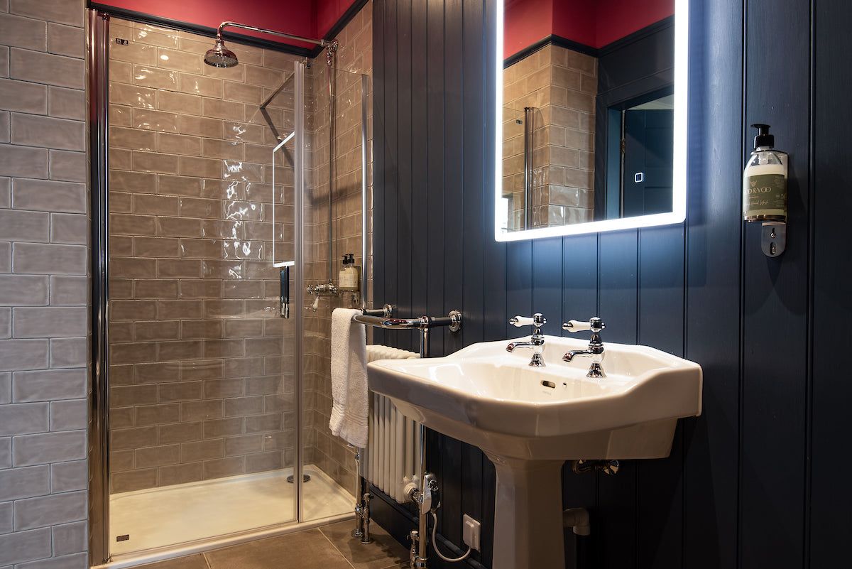 image of a navy blue hotel bathroom. The fixtures are silver and all moo and yoo products can be seen secured to the walls