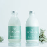 Two bottles of Miracle Hand Wash and Miracle Hand Lotion sitting side by side on a white background with a sprig of moss on each side.