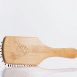 Moo and Yoo bamboo paddle brush showing the cow head logo on the back.