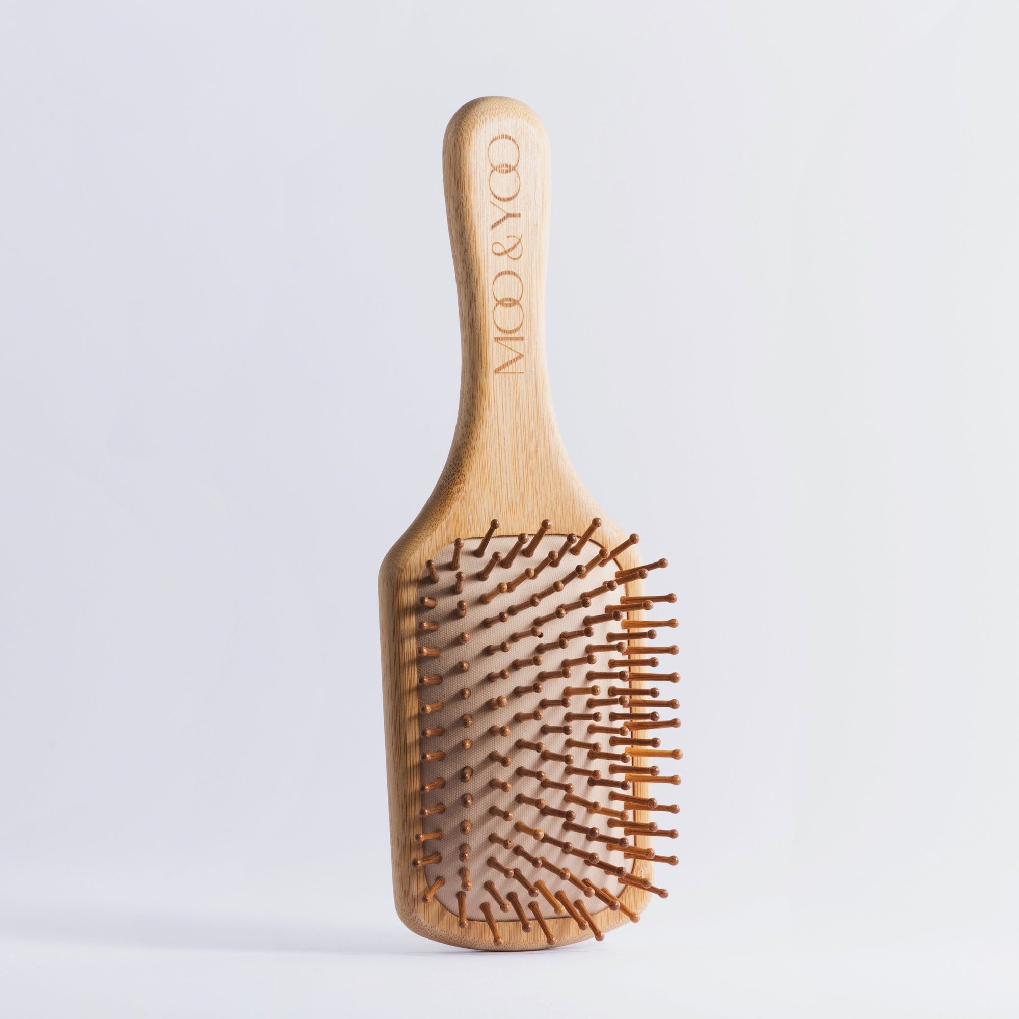 Moi and Yoo bamboo paddle brush with the logo on the handle.