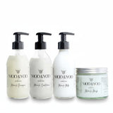 Three glass bottles and a glass jar of Moo and Yoo products sitting side by side. It is a Miracle Shampoo, Conditioner, Miracle Milk and a Miracle mask. They are on a white background.