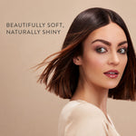 A woman with a shoulder-length dark brown bob haircut and glossy, soft-looking hair is shown against a warm beige background. Text on the left reads, 'BEAUTIFULLY SOFT, NATURALLY SHINY.