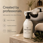 A bottle of MOD & YOO Professional Hair Conditioner with a black pump dispenser, set on a marble counter in a warm, professional salon environment with a shampoo sink and towels in the background.