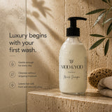 A bottle of MOO & YOO Miracle shampoo stands on a stone ledge in a bathroom setting, with water droplets on the bottle and a sponge nearby. Text on the left reads, 'Luxury begins with your first wash.