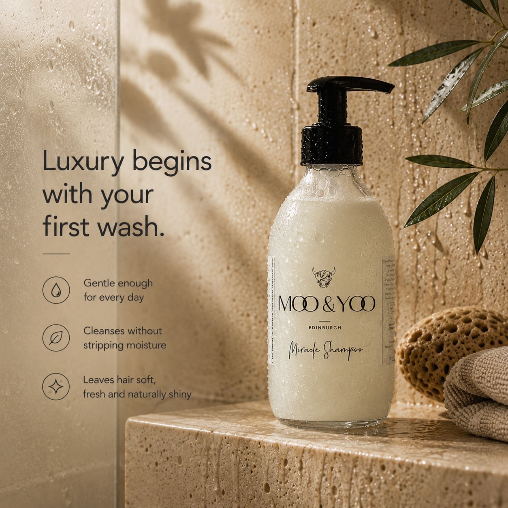 A bottle of MOO & YOO Miracle shampoo stands on a stone ledge in a bathroom setting, with water droplets on the bottle and a sponge nearby. Text on the left reads, 'Luxury begins with your first wash.
