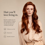 A woman with long, wavy, coppery red hair is shown against a warm beige background, wearing a light beige blouse. Text on the left reads, 'Hair you'll love living in.