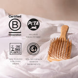 Wooden hairbrush on a white fabric background with sustainability certification logos.