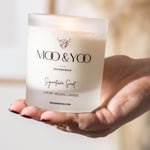Hand holding a MOO & YOO candle with a blurred background