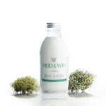 Glass bottle of Miracle Hand Lotion on a white background with a sprig of moss to each side.