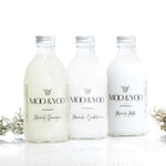 Three glass bottles of Moo and Yoo products sitting side by side. It is a Miracle Shampoo, Conditioner and a Volumising Spray Mist. All have aluminium lids.  They are on a white background with a sprig of Icelandic moss placed to each side.