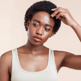Female model with black natural textured hair from using Moo and Yoo Miracle Mask, Miracle Milk and Miracle Curl Crea,.  She has her left hand touching her hair.