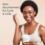 A smiling woman with short dark curly hair holds an open jar of hair product and shows a small amount of the cream on her finger against a warm beige background. Text on the left reads, 'Rich Nourishment for Curls & Coils.