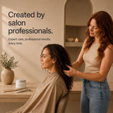 A salon setting with a stylist standing and applying moo & yoo miracle curl cream the hair of a seated client. Text on the left reads, 'Created by salon professionals.