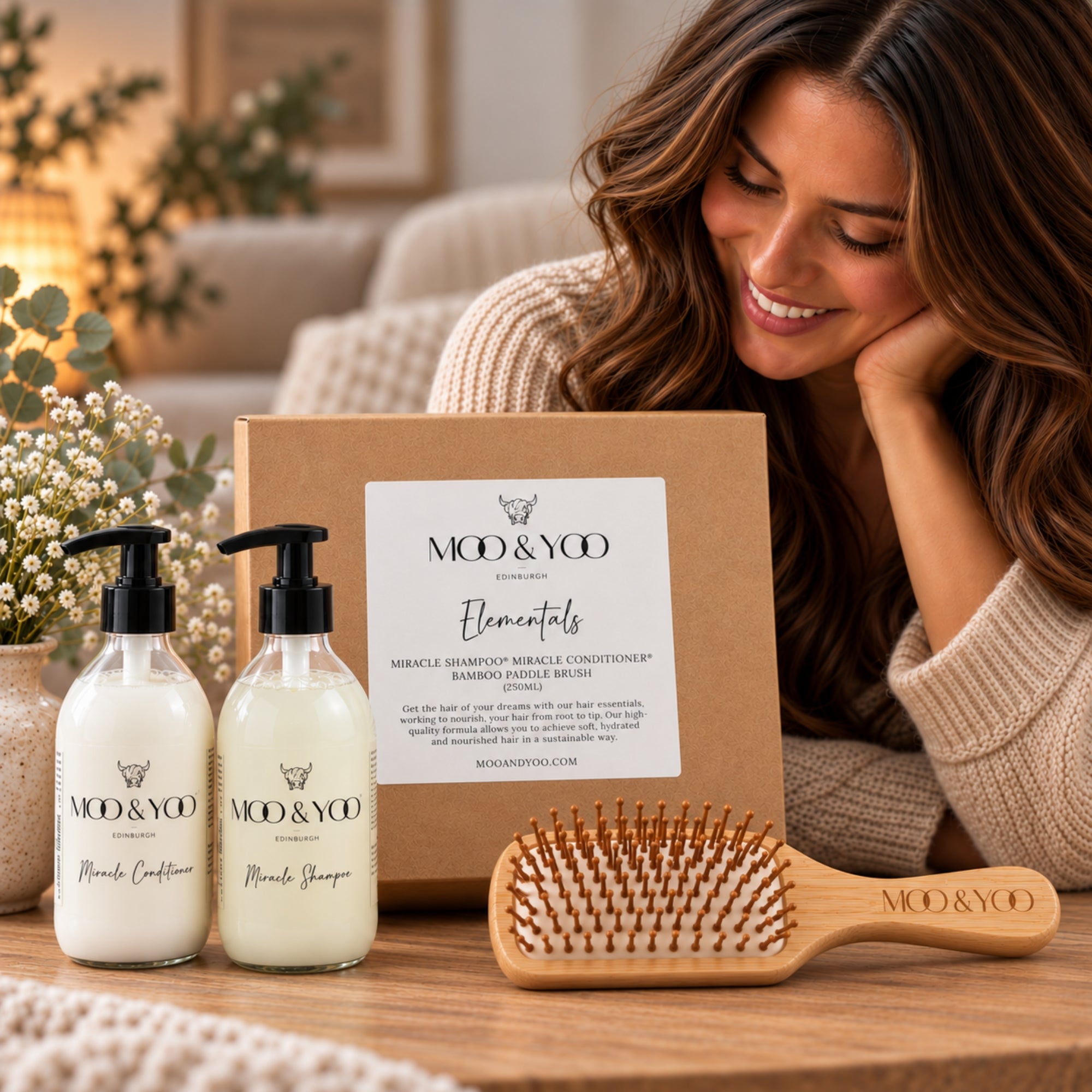 A woman looking at her Moo & Yoo Elementals Gift set which contains miracle shampoo, Miracle conditioner and a bamboo hair brush 