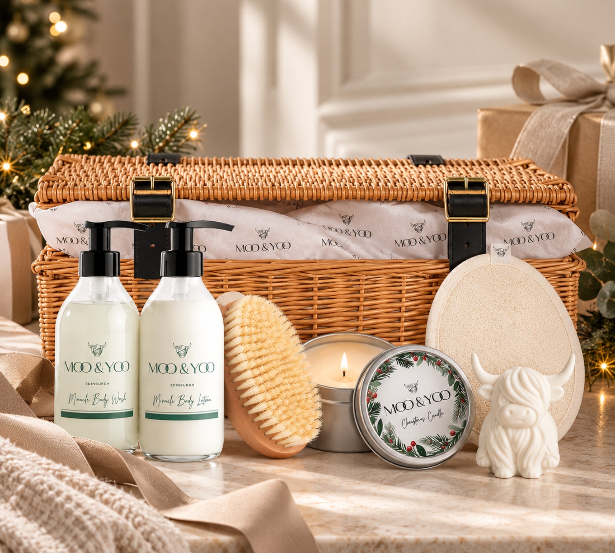 Moo & Yoo Luxury Body Care Christmas Hamper beautifully presented with vegan bodycare, bath accessories and a festive candle in an elegant Christmas setting with warm lights and wrapped gifts.