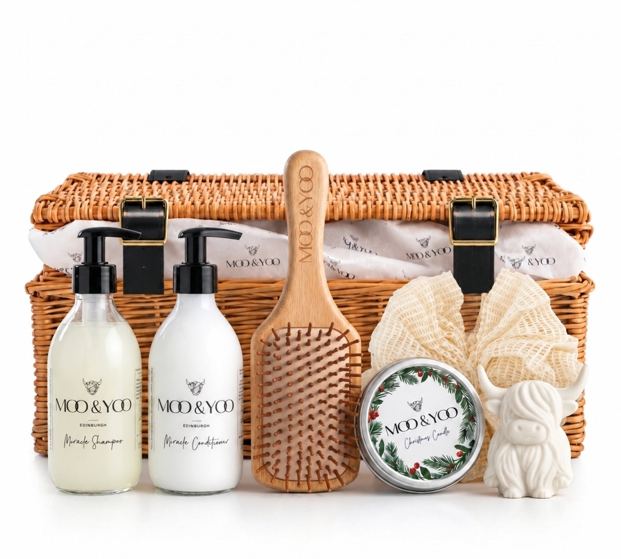 Moo & Yoo Luxury Hair Care Hamper featuring Miracle Shampoo, Miracle Conditioner, bamboo paddle brush, Christmas candle, ramie body buffer and Highland cow soap, presented with branded tissue paper in a wicker gift basket.