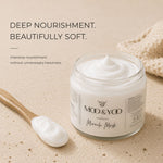 A jar of MOO & YOO  Miracle Mask cream shown on a warm beige textured surface with a wooden spoon holding some of the white mask cream. Text on the left reads 'DEEP NOURISHMENT. BEAUTIFULLY SOFT
