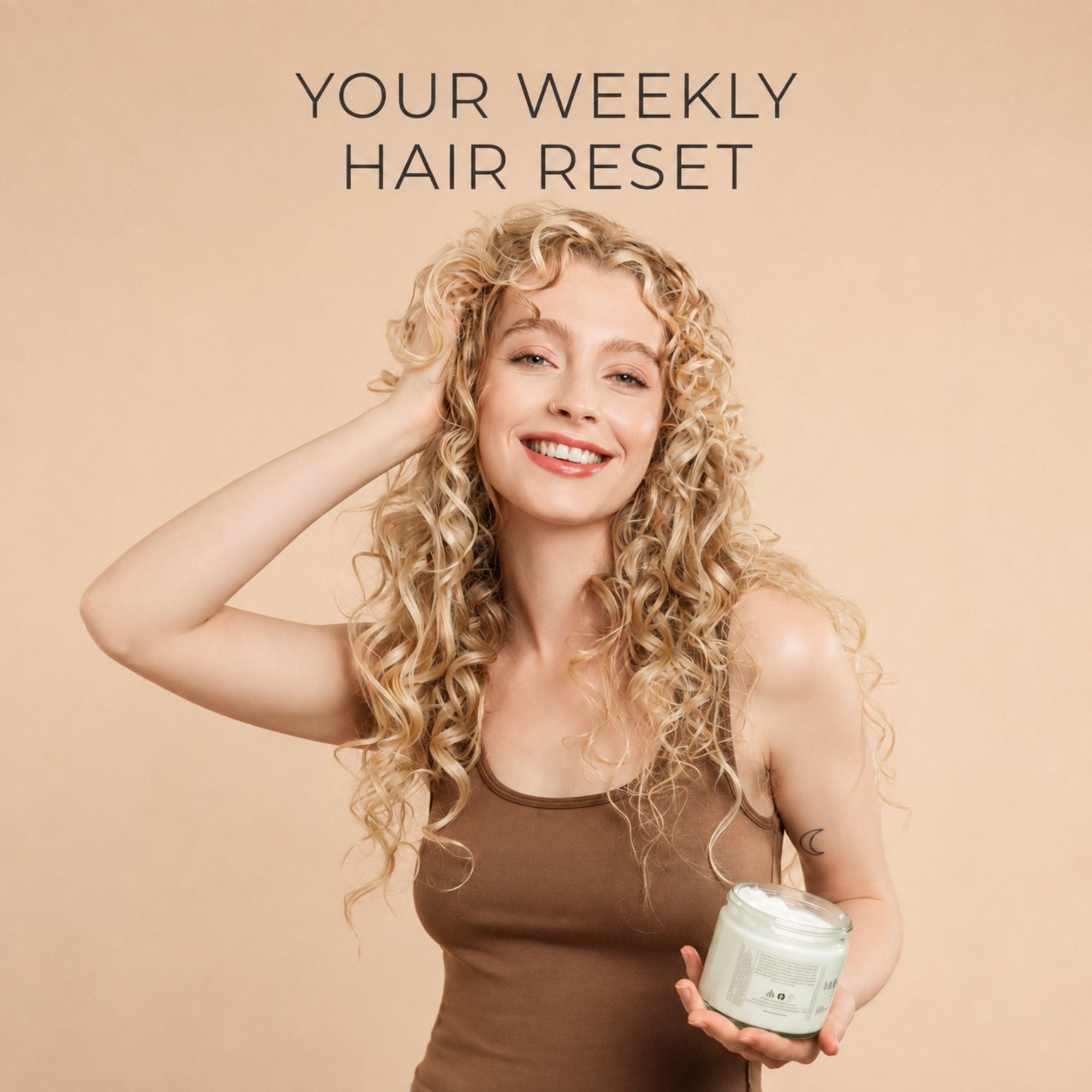 A smiling woman with long curly blonde hair holds a jar of moo and yoo miracle mask hair product against a warm beige background, with the text 'YOUR WEEKLY HAIR RESET' above her.