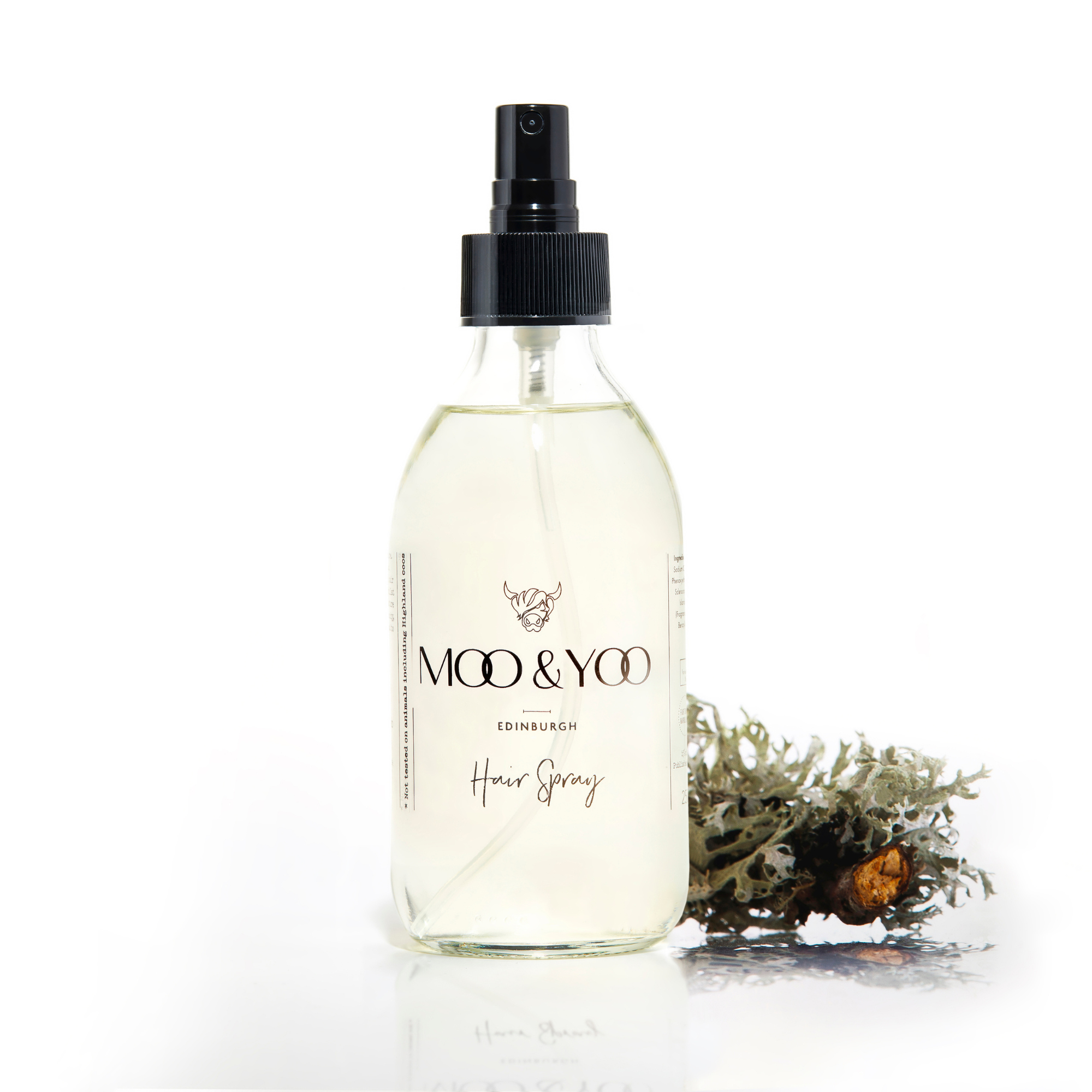 A glass bottle of Moo and Yoo Hair Spray on a white background with a sprig of Icelandic moss placed to one side
