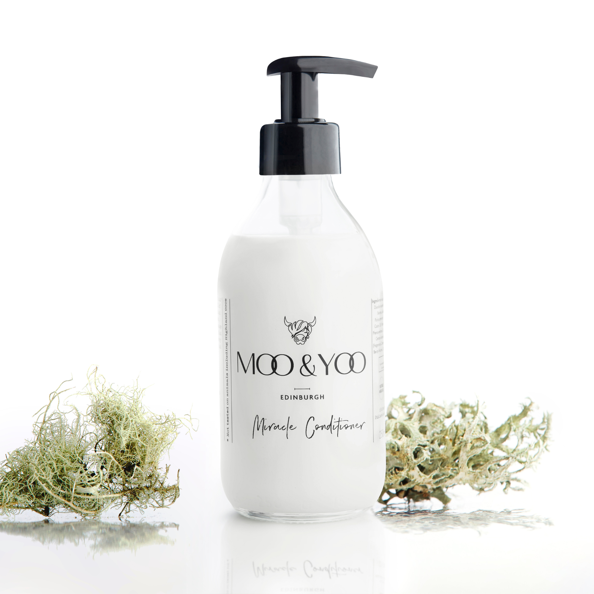 glass bottle of Moo and Yoo Miracle conditioner with a pump top on a white background with a sprig of Icelandic moss placed to each side.