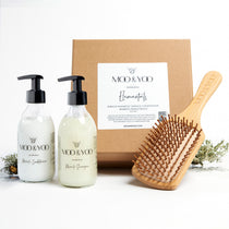 Image of a Kraft natural brown square gift box with label on the front  displaying the gift box name which is Elementals.  The contents of the box are in front of it, Miracle Shampoo, Miracle Conditioner and Bamboo Paddle Brush.