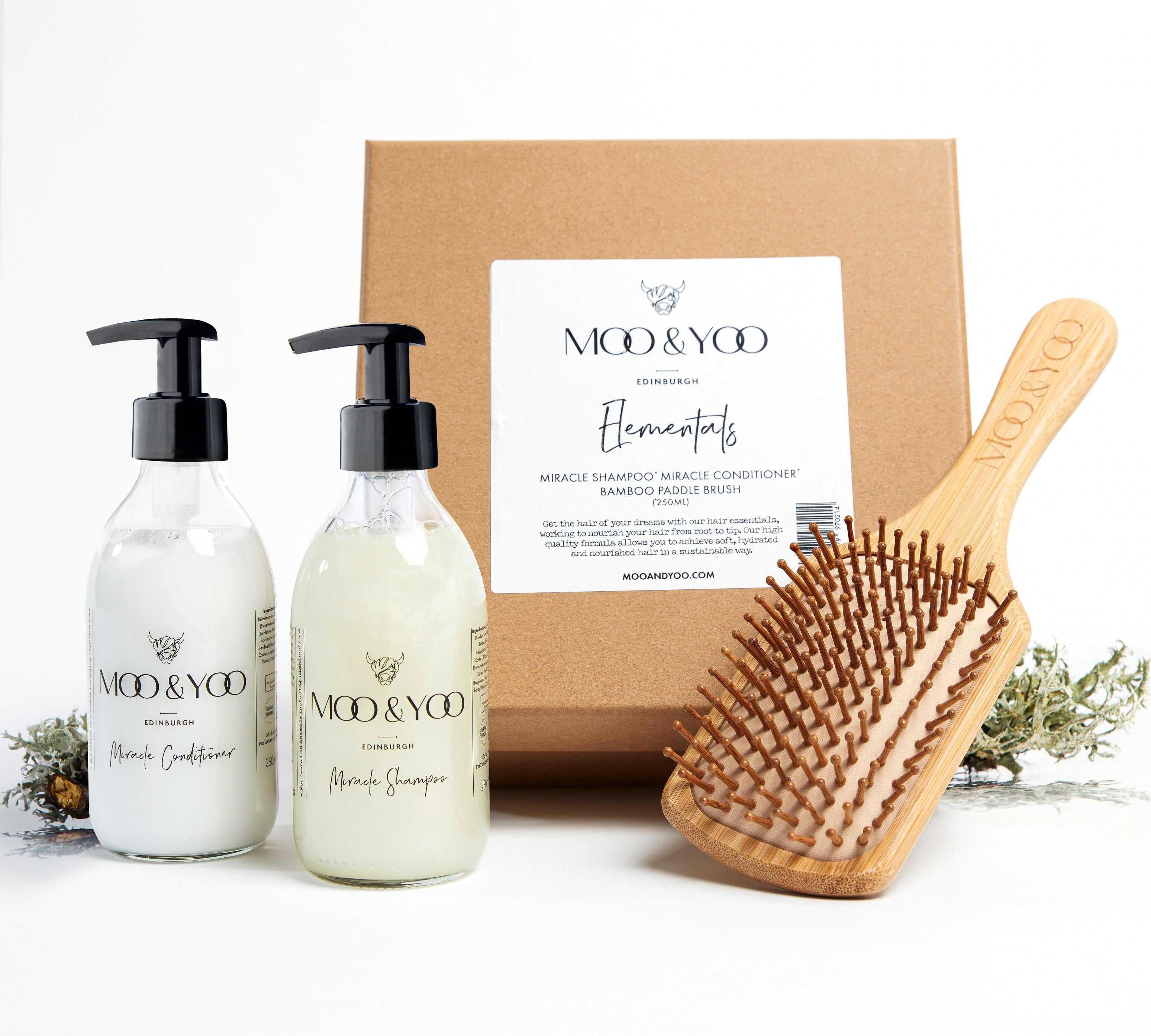 Image of a Kraft natural brown square gift box with label on the front  displaying the gift box name which is Elementals.  The contents of the box are in front of it, Miracle Shampoo, Miracle Conditioner and Bamboo Paddle Brush.