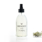 A glass bottle of Moo and Yoo Sea Salt Spray Milk with a spray lid on a white background with a sprig of Icelandic moss placed to one side