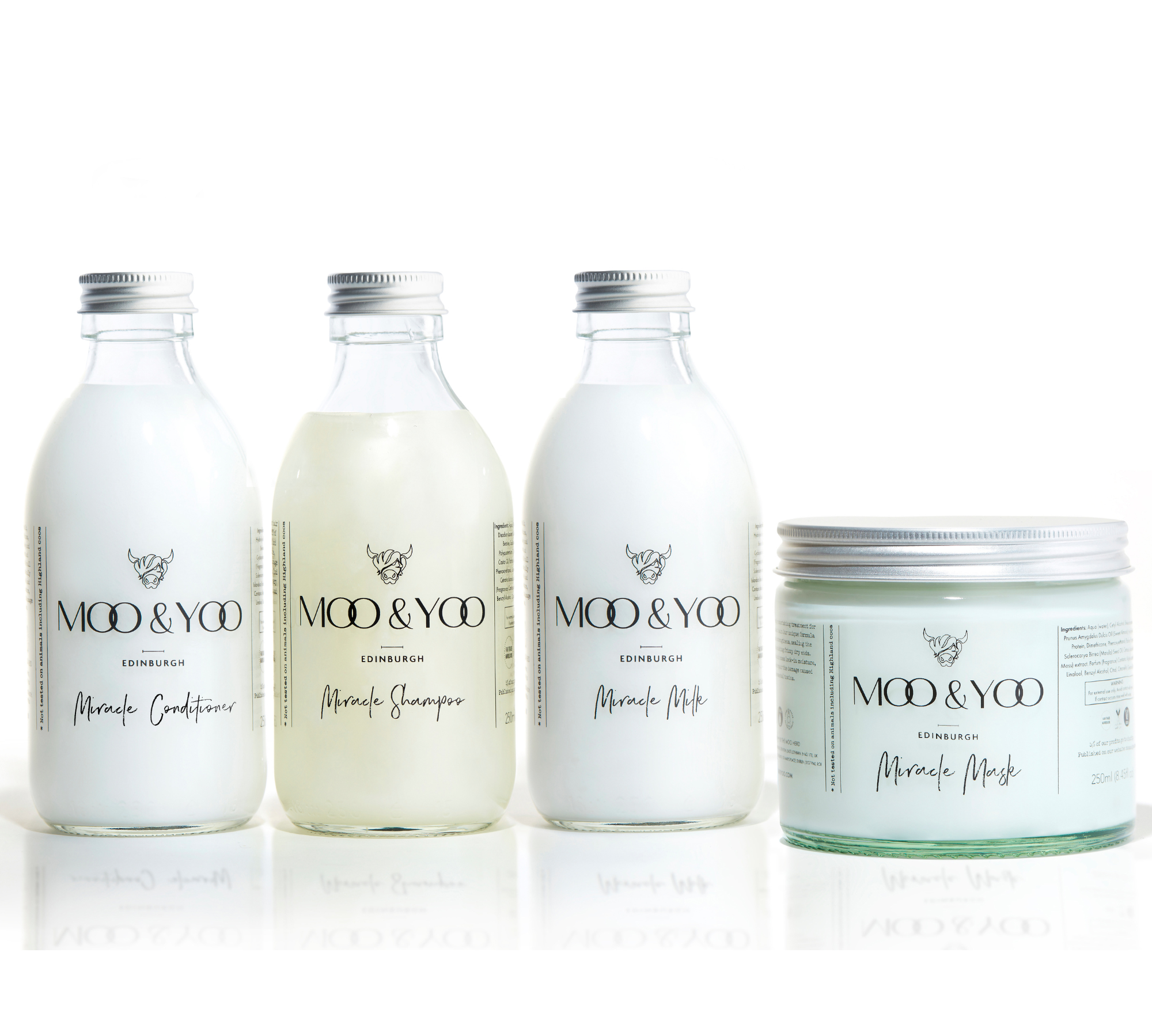 Three glass bottles and a glass jar of Moo and Yoo products sitting side by side. It is a Miracle Shampoo, Conditioner, Miracle Milk and a Miracle mask. They all have aluminium lids.  They are on a white background.