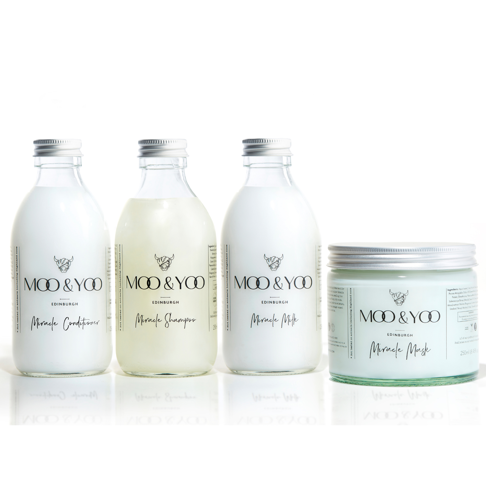 Three glass bottles and a glass jar of Moo and Yoo products sitting side by side. It is a Miracle Shampoo, Conditioner, Miracle Milk and a Miracle mask. They all have aluminium lids.  They are on a white background.