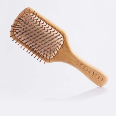 Picture of a bamboo paddle hair brush with the moo and yoo logo on the handle on a white background.
